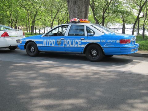 1991 Ford LTD Crown Victoria - blue-and-white NYPD Chevrolet Caprice marked POLICE, unit 1350, 103 PCT, with roof lights, seen from the rear three-quarter.