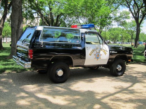 1991 Ford LTD Crown Victoria - black-and-white 'Highway Patrol' SUV with roof light bar and star emblem, parked on gravel under shade trees in a park.