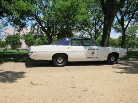 1991 Ford LTD Crown Victoria - white 'New York State Police' four-door sedan with door shield emblem, parked on gravel beneath shade trees.