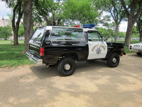 1991 Ford LTD Crown Victoria - Rear three-quarter view of a black and white 'Highway Patrol' Dodge Ramcharger SUV with light bar, parked on grass.