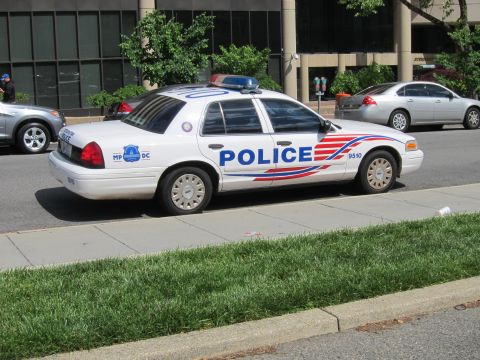 1991 Ford LTD Crown Victoria - white Ford Crown Victoria police cruiser marked POLICE with red and blue striping parked along a grassy curb.