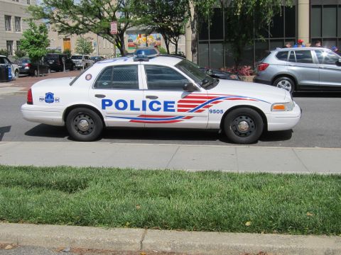 1991 Ford LTD Crown Victoria - white Ford Crown Victoria police cruiser marked POLICE 9505 shown in side profile beside a grassy verge.