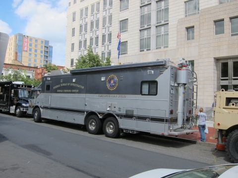1991 Ford LTD Crown Victoria - large gray FBI Mobile Command Center truck with seal decal parked along a downtown street beside other vehicles.
