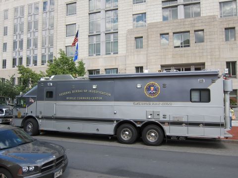 1991 Ford LTD Crown Victoria - side view of a gray FBI Mobile Command Center truck with seal decal parked along a city street near a flagpole.