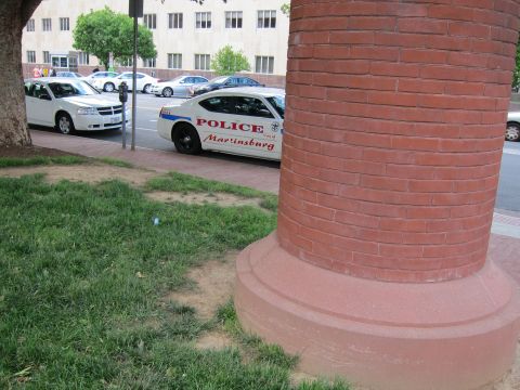 1991 Ford LTD Crown Victoria - white City of Martinsburg police sedan parked on a street, seen past a red brick column and grass.