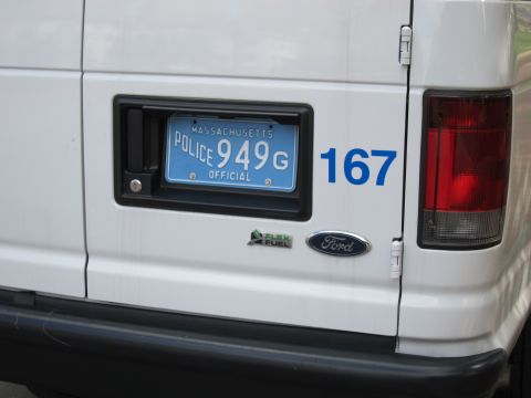 1991 Ford LTD Crown Victoria - Rear close-up of a white Ford Flex Fuel police van showing a blue Massachusetts official plate and unit number 167.