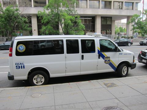 1991 Ford LTD Crown Victoria - white police Chevrolet passenger van marked Highway Patrol and Dial 911 parked at a city curb.