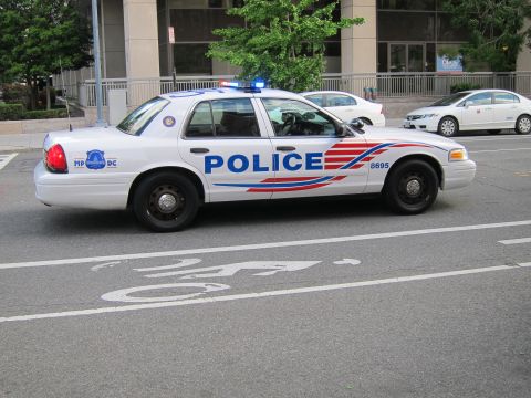 1991 Ford LTD Crown Victoria - white Metropolitan Police DC Ford sedan marked 8695 with red and blue striping and blue roof lights on a street.