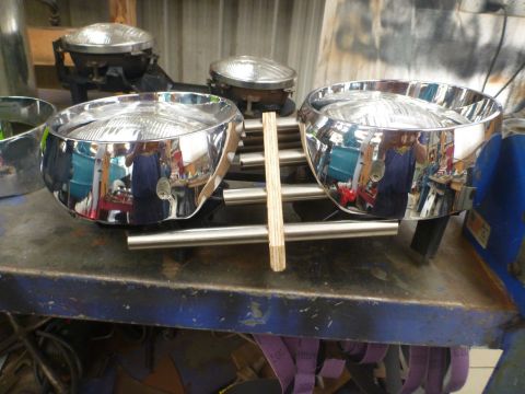 1964 Mercury Monterey - Two chrome headlight bezels are displayed on a workbench, possibly for restoration or sale.