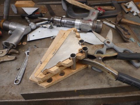 1964 Mercury Monterey - A metal jig is clamped to a workbench, surrounded by various tools used for fabrication.