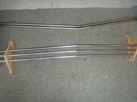 1964 Mercury Monterey - Several long, thin chrome trim pieces are laid out on a carpeted surface, some secured by wooden blocks.