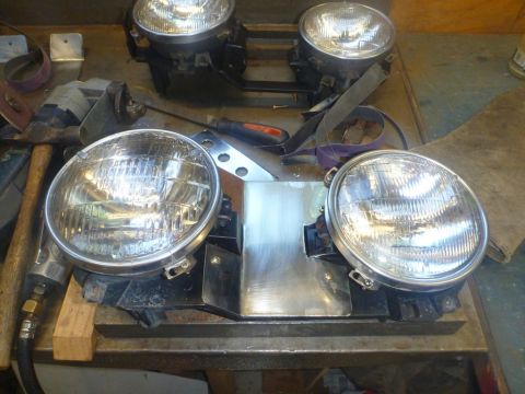 1964 Mercury Monterey - A collection of four round headlights are laid out on a workbench, suggesting a repair or restoration project.