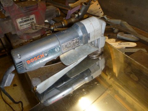 1964 Mercury Monterey - A Bosch metal shear tool is shown resting on a reflective surface, with a vise and other workshop items in the background.