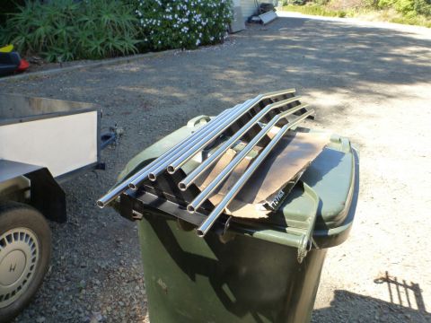 1964 Mercury Monterey - Several chrome grille sections are piled on top of a large green garbage can, with a trailer visible to the left.