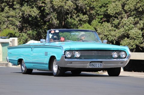 1964 Mercury Monterey - A turquoise convertible cruises down the road, a distinctive grille and dual headlights.