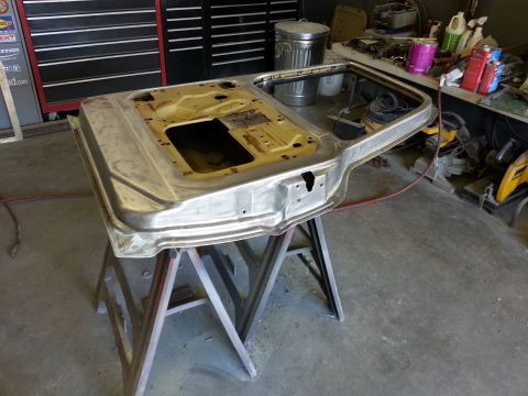 1967 Ford F-100 - A bare metal truck door is prepped for restoration, resting on sawhorses in a cluttered garage setting.