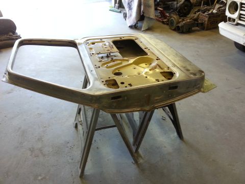 1967 Ford F-100 - A bare car door is set up on sawhorses in a workshop, ready for restoration or repair.