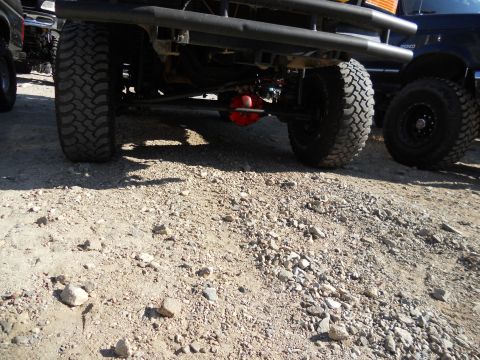 1986 Ford Bronco - The rear underside of a lifted 1987 Ford Bronco is visible, showing its large tires and a red differential.