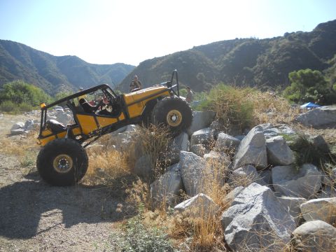 1986 Ford Bronco - Custom off-road buggy tackling a challenging rocky terrain on a sunny day.