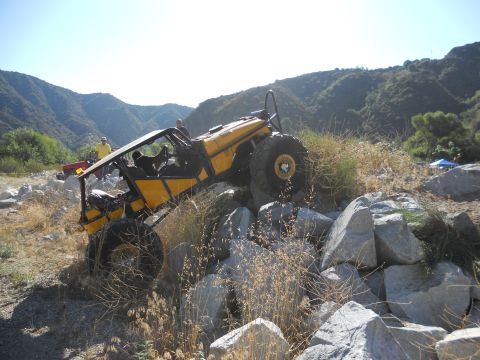 1986 Ford Bronco - A yellow buggy navigates a rocky terrain in a mountainous, arid environment.