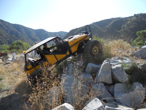 1986 Ford Bronco - Off-road buggy tackles a challenging rocky terrain on a sunny day.