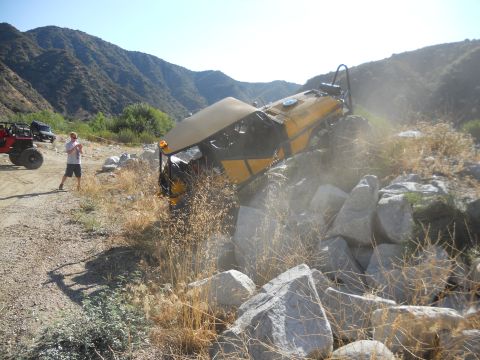 1986 Ford Bronco - An off-road vehicle is stuck on a rocky incline, with another vehicle and a person observing the situation.