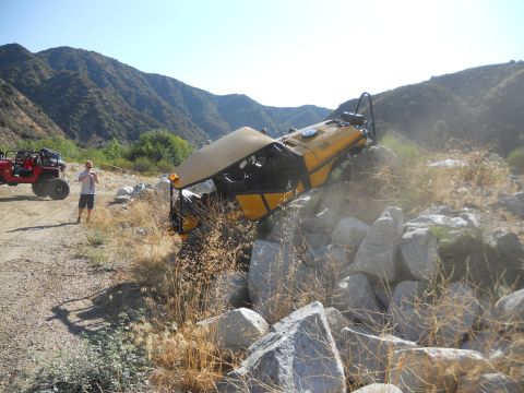 1986 Ford Bronco - An off-road vehicle is stuck on rocks, with another ATV nearby.