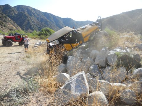 1986 Ford Bronco - Two off-road vehicles navigate a rocky trail in a mountainous area.