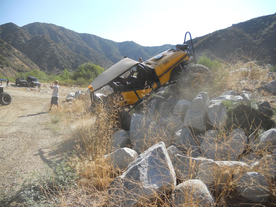 yellow buggy stuck on rocks, person filming