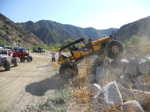 1986 Ford Bronco - Multiple off-road vehicles navigate a rocky terrain under a clear blue sky.