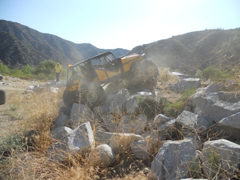 1986 Ford Bronco - Off-road vehicle attempts to climb over large rocks in a dry, mountainous area.