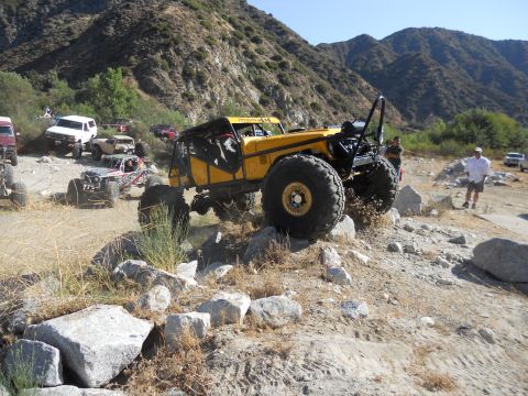 1986 Ford Bronco - A group of off-road vehicles navigate a rocky trail in a mountainous area.