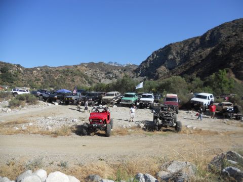 1986 Ford Bronco - A collection of off-road vehicles are parked in a scenic, mountainous area under a clear blue sky.