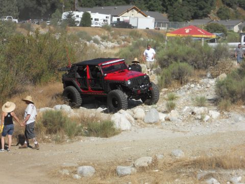 1986 Ford Bronco - Modified red Jeep Wrangler tackling a challenging off-road course.