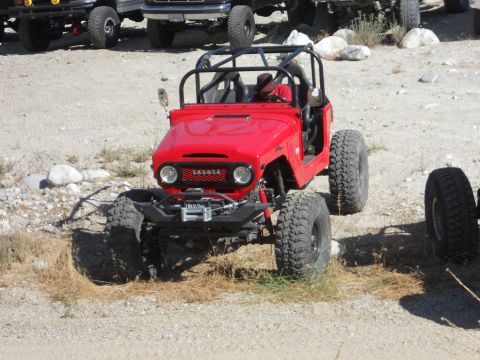 1986 Ford Bronco - A modified red Toyota Land Cruiser FJ40 is parked outdoors with other vehicles visible in the background.