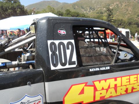 1986 Ford Bronco - Side view of a race truck with prominent sponsor decals and driver name.