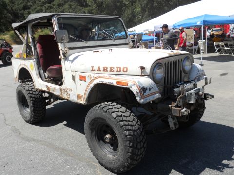 1986 Ford Bronco - This Jeep CJ-7 Laredo, seen in a three-quarter front view, is modified with off-road tires and a lifted suspension.