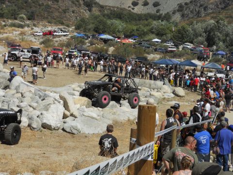 1986 Ford Bronco - A crowd gathers to watch an off-road buggy tackle a rocky obstacle course during an event.