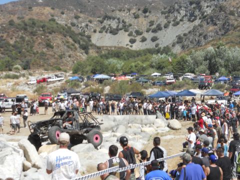 1986 Ford Bronco - A custom off-road buggy with pink wheels is seen navigating a rocky terrain during an event.