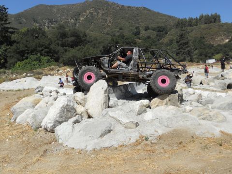 1986 Ford Bronco - A custom-built off-road buggy navigates a challenging rocky terrain under a clear sky.