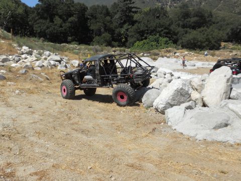 1986 Ford Bronco - This heavily modified off-road buggy navigates a rocky trail, with another vehicle visible in the background.
