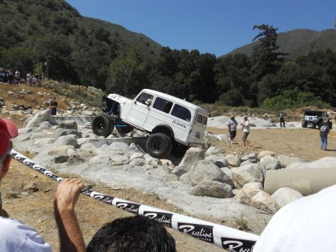 1986 Ford Bronco - A modified wagon navigates a challenging off-road course with spectators watching.