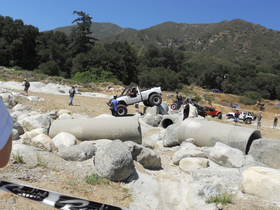 White pickup truck navigating rocky terrain and concrete pipes