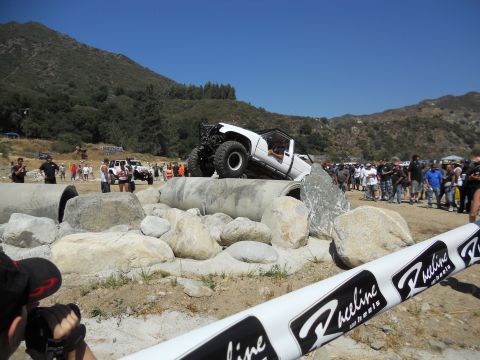 1986 Ford Bronco - Spectators gather to watch a modified off-road vehicle navigate a challenging obstacle course.