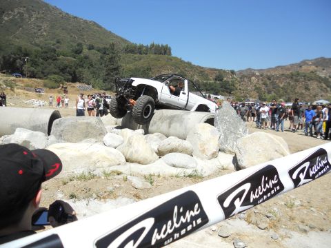 1986 Ford Bronco - Off-road truck competes in an obstacle course event with spectators present.