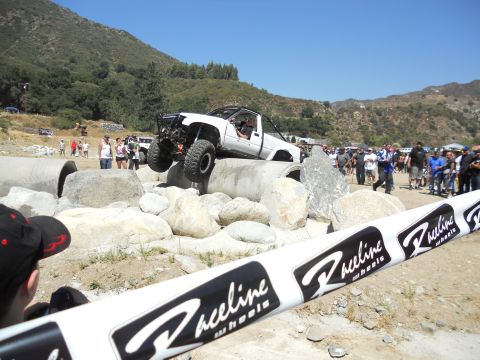 1986 Ford Bronco - A modified off-road truck navigates a challenging obstacle course on a sunny day.