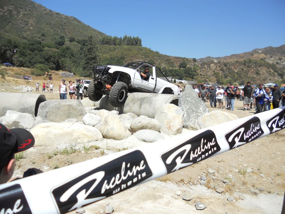 White off-road truck with large tires navigating a rocky obstacle course