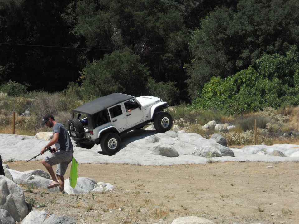White Jeep Wrangler climbing over rocks on a dirt trail
