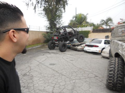 1986 Ford Bronco - An off-road buggy is positioned on top of several damaged cars, suggesting a car crush event.
