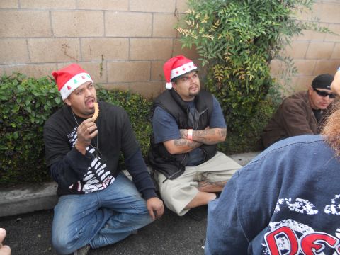 1986 Ford Bronco - Men in Santa hats gather outdoors, with one enjoying a churro during what appears to be a holiday event.